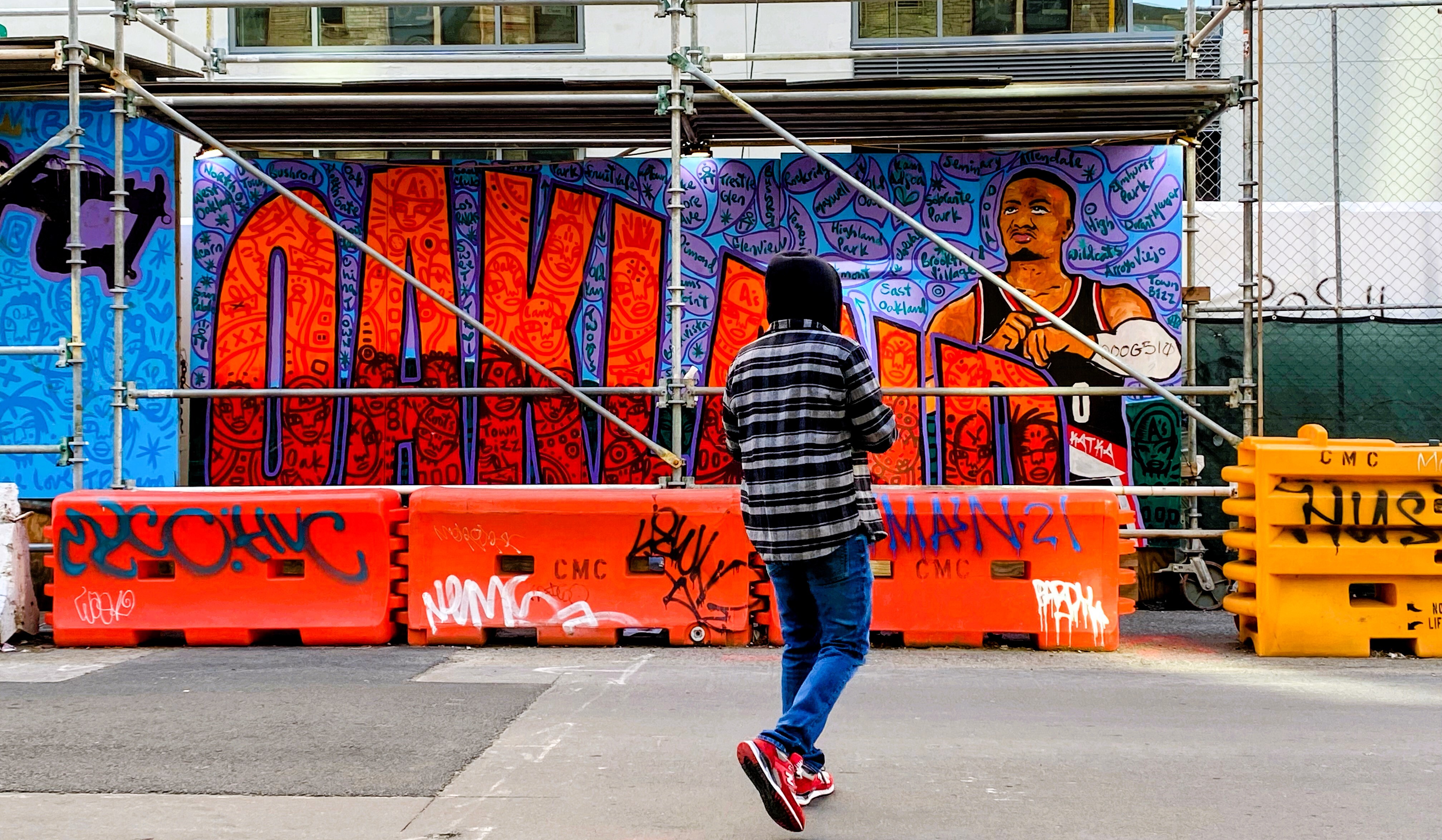 Person standing in front of mural of the word Oakland with Damian Lillard