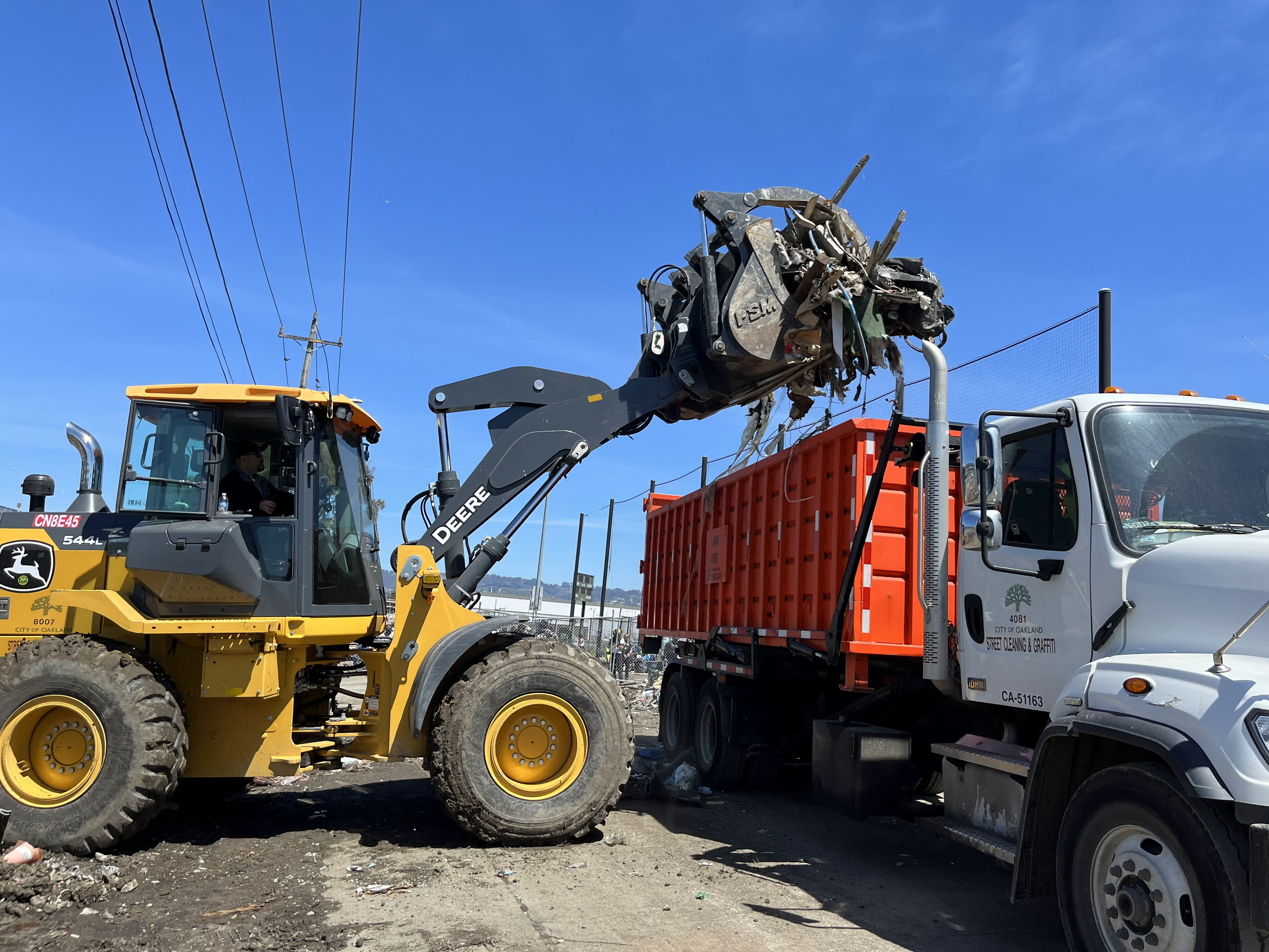 front loader truck unloading debris into a dump truck