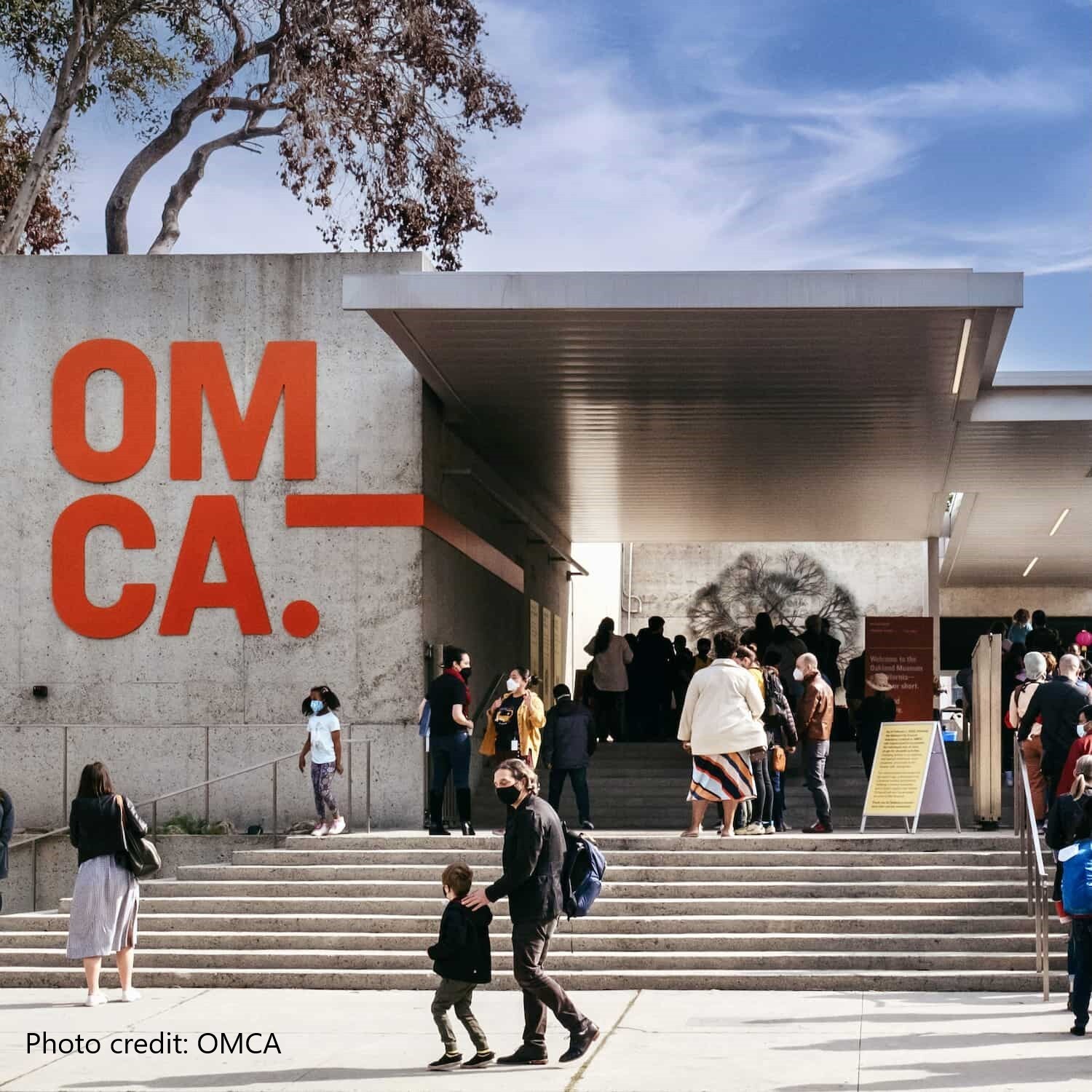 People on the steps of OMCA, in front of the iconic "OM--CA" red letters