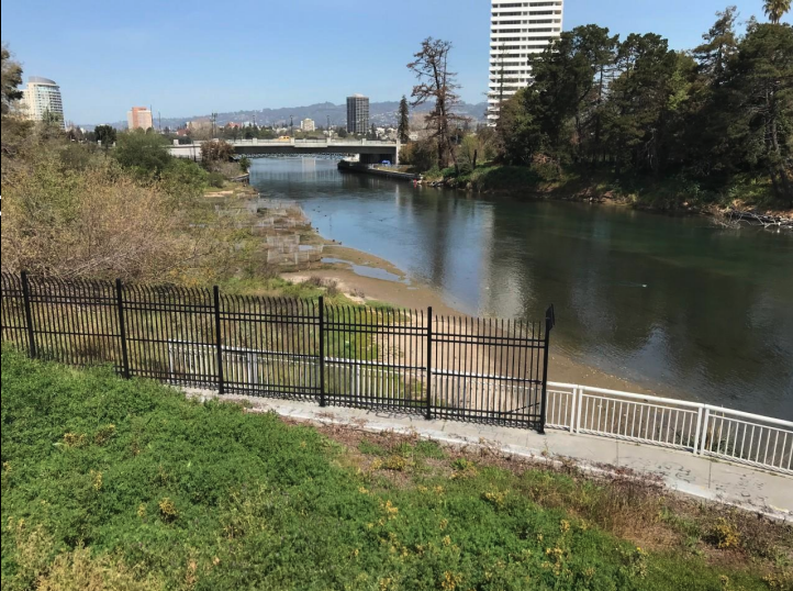A view of the Lake Merritt Channel from the 10th Street bridge toward the lake, with a new black fence around the Marsh between those bridges.