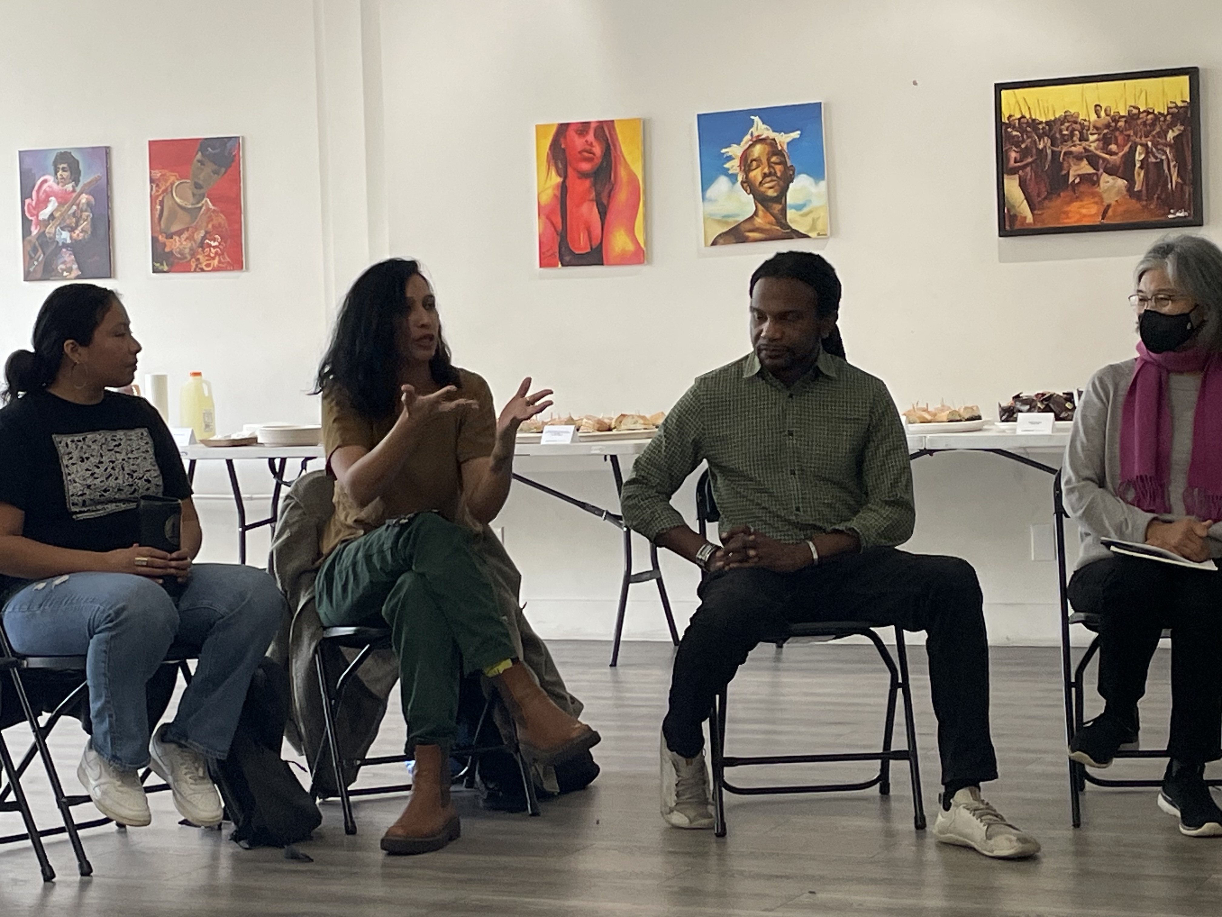 four panelists sit on chairs in an art gallery setting