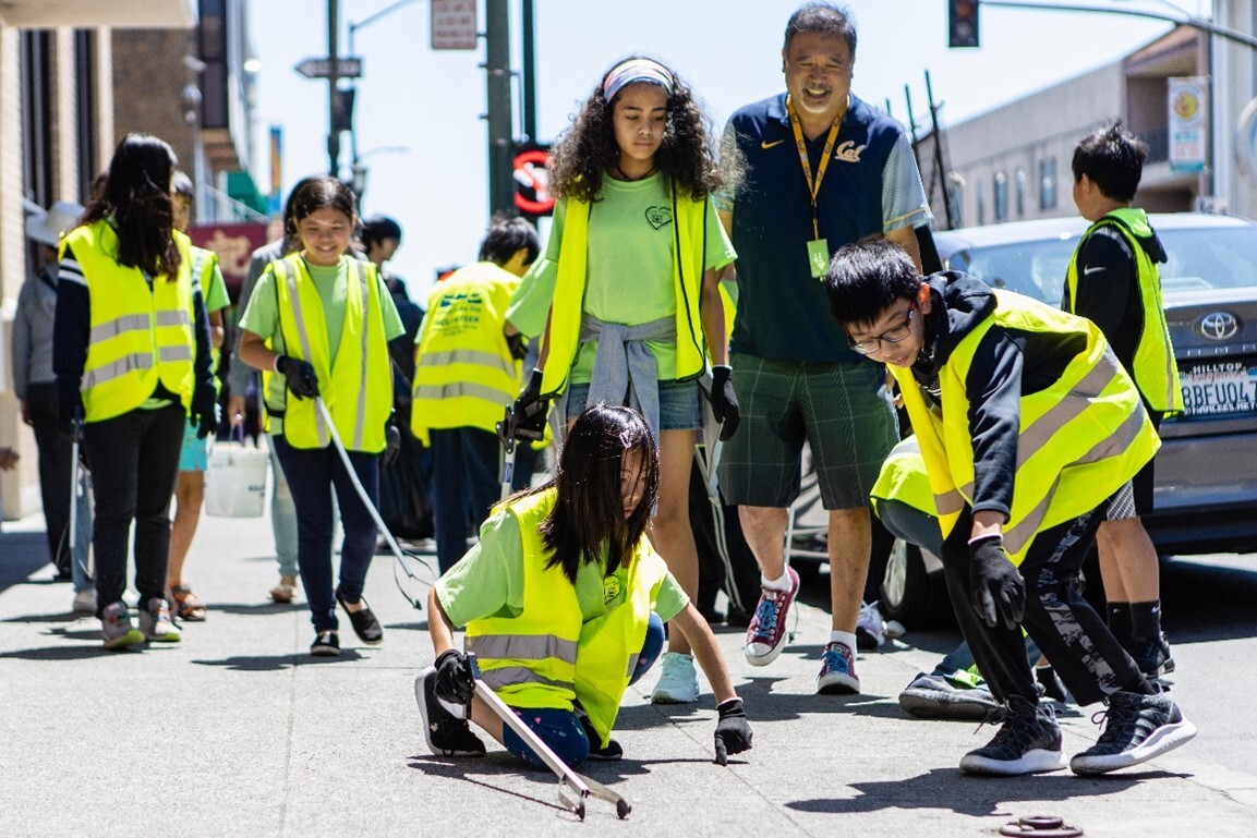 volunteers in yellow vests pick up litter