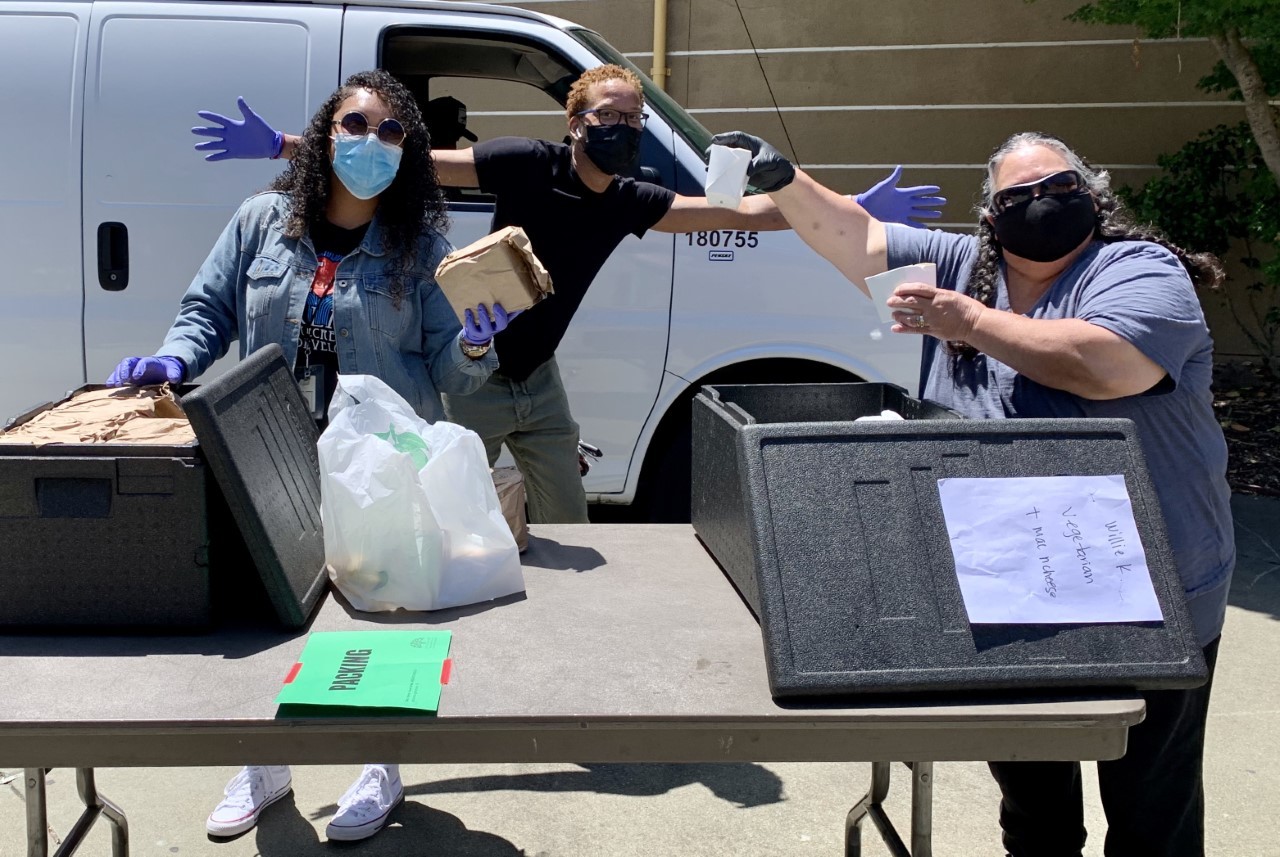 Three people display meals provided by the Summer Lunch Program.